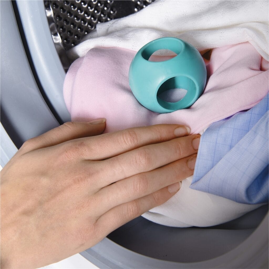 main qui met une boule anti-calcaire dans le lave-linge