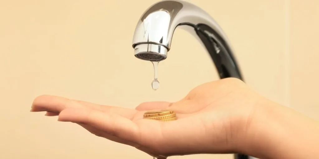 MAin qui retient une goutte d'eau ui fuit d'un robinet